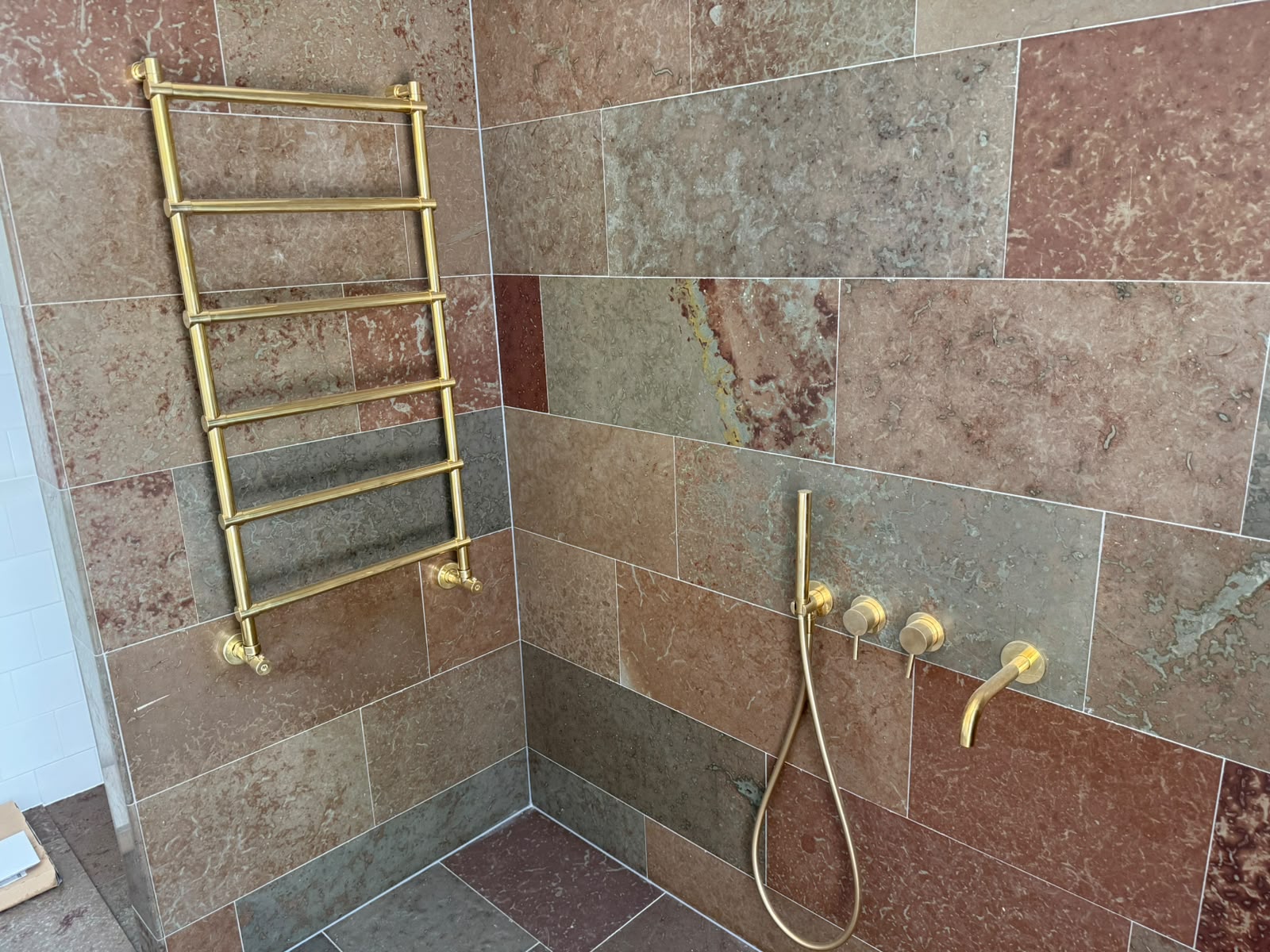 Bathroom with terrazzo tiles on walls and floor, brass taps and towel rail